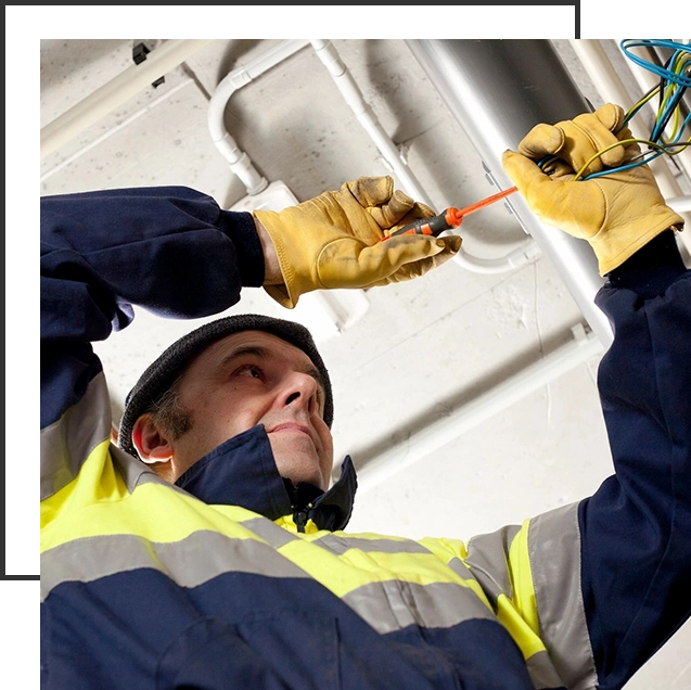 A man in yellow and blue jacket holding wires.